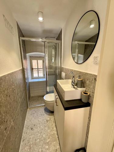 a bathroom with a sink and a toilet and a mirror at Bel Composto Apartments in Perast
