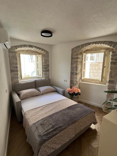 a bedroom with a large bed and two windows at Bel Composto Apartments in Perast