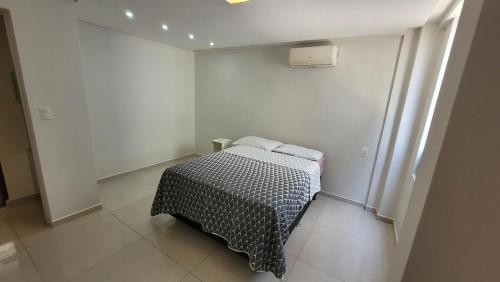 a small bedroom with a bed in a white room at Cantinho do Caribe Paraibano in João Pessoa