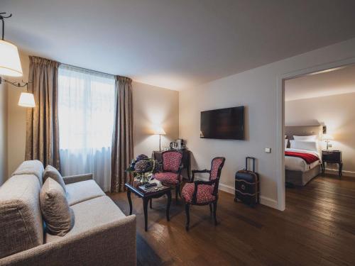 a hotel room with a couch and chairs and a bed at Cour du Corbeau Hotel Strasbourg - MGallery Collection in Strasbourg