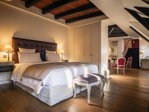 a bedroom with a large bed and a table and chairs at Cour du Corbeau Hotel Strasbourg - MGallery Collection in Strasbourg