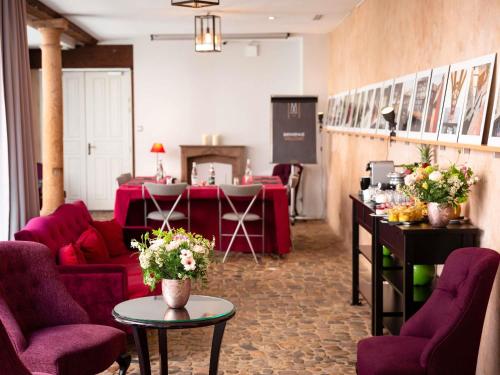 a waiting room with purple chairs and a table with flowers at Cour du Corbeau Hotel Strasbourg - MGallery Collection in Strasbourg