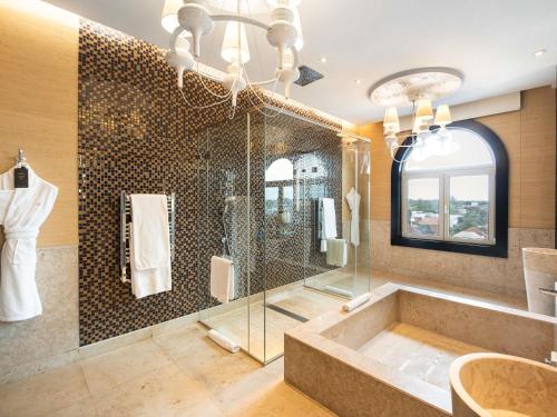 a bathroom with a tub and a glass shower at Sofitel Montevideo Casino Carrasco & Spa in Montevideo