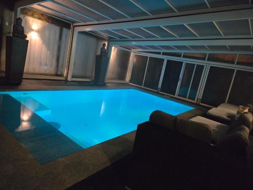 a swimming pool in a building with a couch and a table at Bed & Wellness Angie in Almere