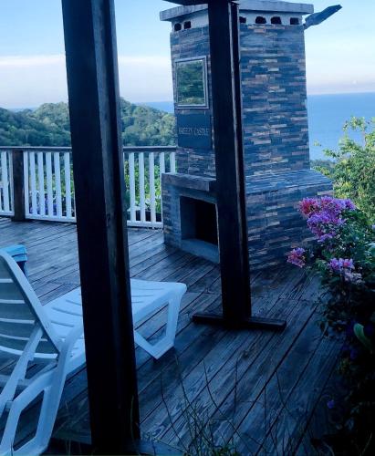 a porch with a fireplace and a chair on a deck at Breezy Castle Villa with private pool overlooking the Sea and Blue Mountains in Port Maria
