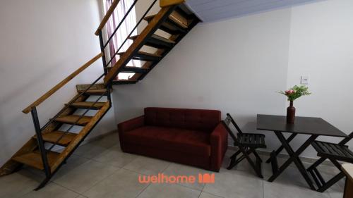 ein Wohnzimmer mit einem roten Sofa und einer Treppe in der Unterkunft Studio em Ponta Grossa com Excelente Localizacao in Ponta Grossa