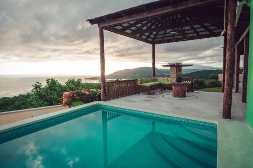 a swimming pool with a gazebo and a table at Breezy Castle Villa with private pool overlooking the Sea and Blue Mountains in Port Maria
