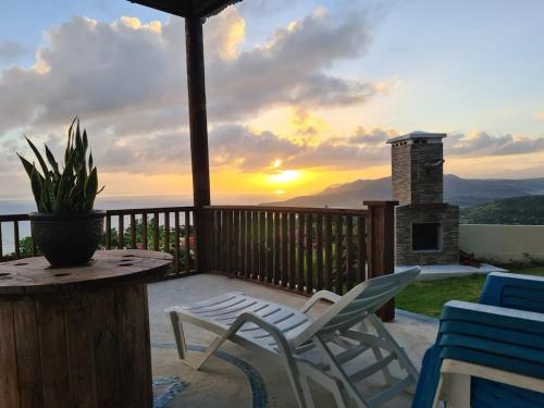 a patio with chairs and a table with a sunset in the background at Breezy Castle Villa with private pool overlooking the Sea and Blue Mountains in Port Maria