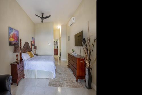 a bedroom with a bed and a dresser and a tv at Breezy Castle Villa with private pool overlooking the Sea and Blue Mountains in Port Maria