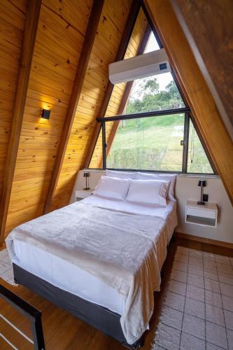 a bed in a room with a large window at Chalé Encanto de Maria em Teresópolis in Teresópolis