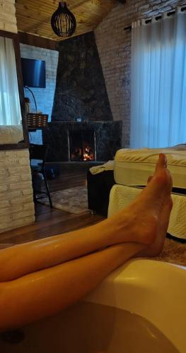 a persons leg laying on a tub in a room with a fireplace at Chalé Sonho Diniz 3 in Monte Verde