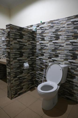 a bathroom with a toilet and a brick wall at Anugerah Villas in Amed