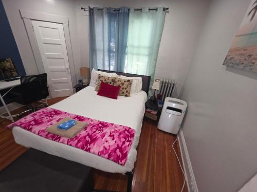 a bedroom with a white bed with a pink blanket at downtown and secluded in Manchester