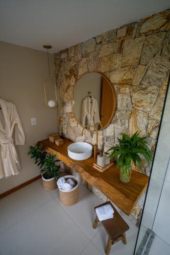 a bathroom with a stone wall with a sink and a mirror at Chalé Encanto de Maria em Teresópolis in Teresópolis