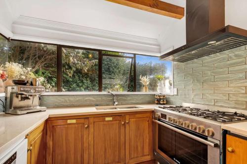 a kitchen with wooden cabinets and a stove top oven at Redwoods Lodge - 6BR & 6BA - Large Groups - Free Parking in Rotorua