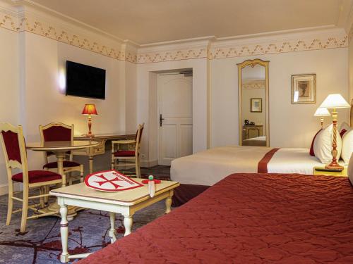a hotel room with two beds and a desk at Hotel de la Cité Carcassonne - MGallery Collection in Carcassonne