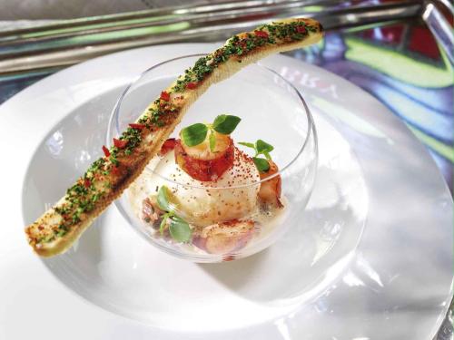 a white plate with a dish of food on it at Hotel de la Cité Carcassonne - MGallery Collection in Carcassonne