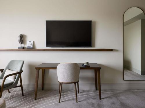 a room with a table with a television and a chair at The Playford Adelaide - MGallery in Adelaide