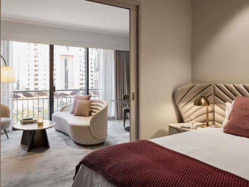 a hotel room with a bed and a chair and a large mirror at The Playford Adelaide - MGallery in Adelaide