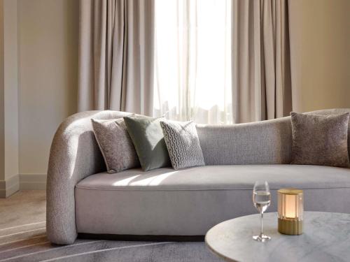 a living room with a grey couch with a wine glass at The Playford Adelaide - MGallery in Adelaide