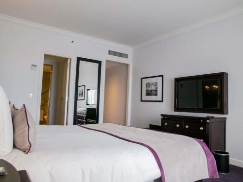 a bedroom with a white bed and a flat screen tv at Sofitel Buenos Aires Recoleta in Buenos Aires