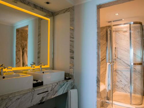 a bathroom with two sinks and a shower with a mirror at Sofitel Buenos Aires Recoleta in Buenos Aires