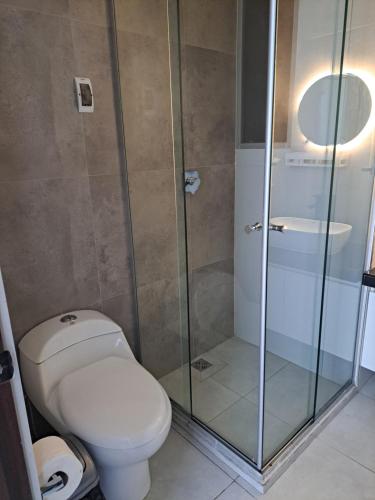 ein Badezimmer mit Toilette und Glasdusche in der Unterkunft Cómodo departamento en barrio petrolero in Sucre