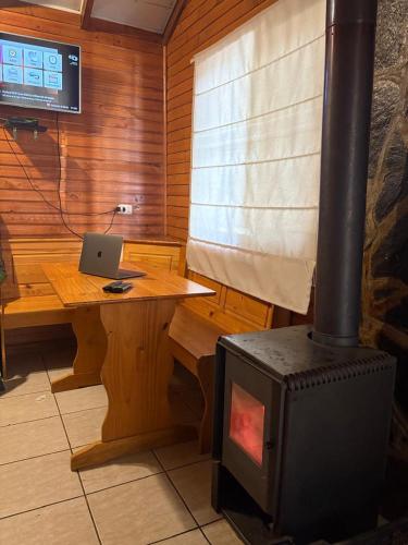 a room with a stove and a laptop on a table at cabañas turismo las trancas in Las Trancas