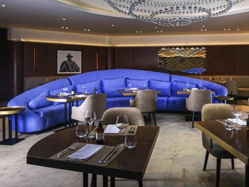 a dining room with a blue couch and tables at Sofitel Buenos Aires Recoleta in Buenos Aires