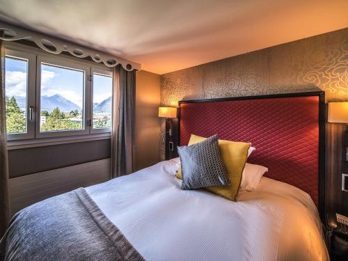 a bedroom with a large bed with two windows at Royal St. Georges Hotel Interlaken - MGallery Collection in Interlaken