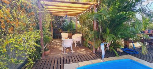 a wooden deck with a table and chairs and a pool at Mira Playa Geribá in Búzios