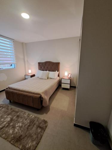 ein Schlafzimmer mit einem Bett und zwei Lampen an zwei Tischen in der Unterkunft Cómodo departamento en barrio petrolero in Sucre