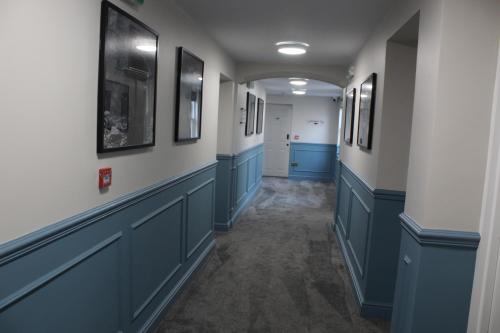 a hallway with blue cabinets and pictures on the walls at The Royal Alfred in Saint Helens