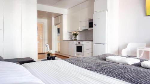 a white bedroom with a bed and a kitchen at Heart of Oulu studio Parking in Oulu