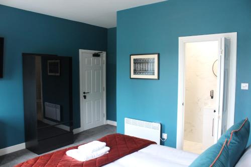 a bedroom with blue walls and a bed with a red blanket at The Royal Alfred in Saint Helens