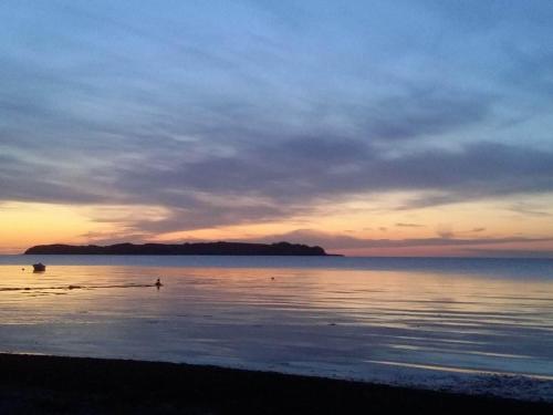 a sunset on the beach with a boat in the water at 5 person holiday home in Føllenslev-By Traum in Føllenslev