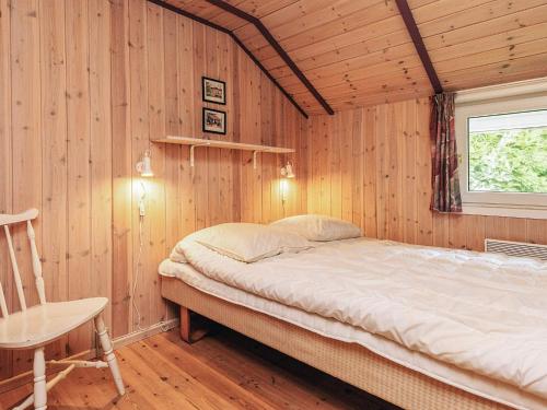 ein Schlafzimmer mit einem Bett in einer Holzwand in der Unterkunft Luxurious Retreat by Bratten Strand-By Traum in Jerup