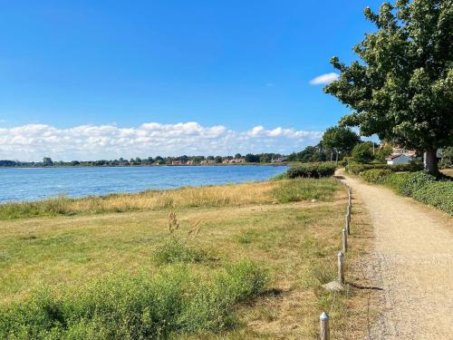 a walking path next to a lake with a tree at Charming Retreat by Water - By Traum Ferienwohnungen in Nykøbing Sjælland