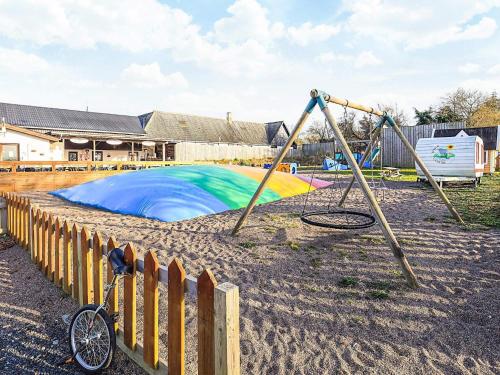 a playground with a swing and a bike next to a fence at 3 person holiday park home in Gørlev in Gørlev