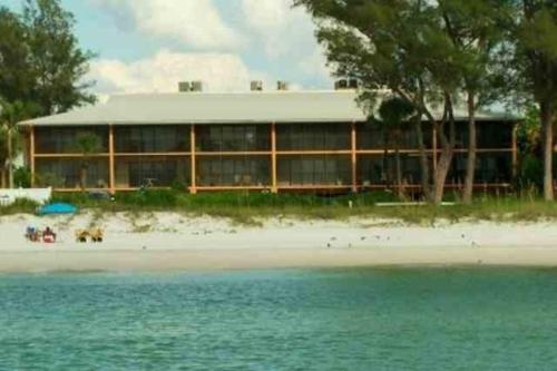 a building on the beach with a beach and water at Sunset Beach Condo #54455 in Holmes Beach