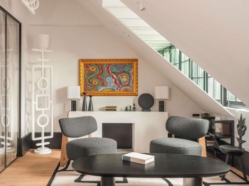 a living room with a table and chairs and a painting at Balthazar Hotel & Spa Rennes - MGallery Collection in Rennes