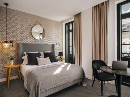 a bedroom with a bed and a table with a laptop at Balthazar Hotel & Spa Rennes - MGallery Collection in Rennes