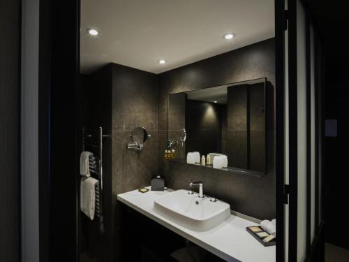 a bathroom with a sink and a mirror at Balthazar Hotel & Spa Rennes - MGallery Collection in Rennes