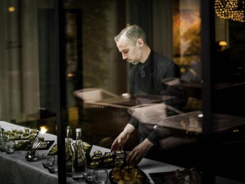 a man standing next to a table with wine bottles at Balthazar Hotel & Spa Rennes - MGallery Collection in Rennes