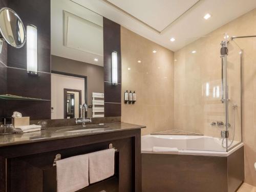 a bathroom with a tub and a sink and a shower at La Citadelle Hotel Metz - MGallery Collection in Metz