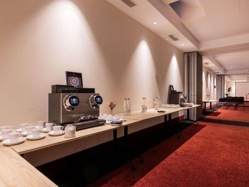 a large room with a long table with cups and dishes at La Citadelle Hotel Metz - MGallery Collection in Metz