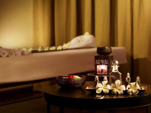 a room with a bed and a table with a bottle of perfume at The Lake Garden Hotel Nay Pyi Taw - MGallery Collection in Nay Pyi Taw