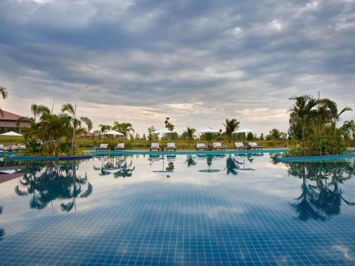 a large swimming pool with chairs and palm trees at The Lake Garden Hotel Nay Pyi Taw - MGallery Collection in Nay Pyi Taw