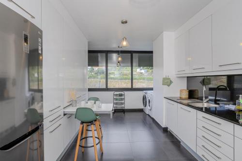 a kitchen with white cabinets and a green stool at Neat Apartment in Ponta Delgada