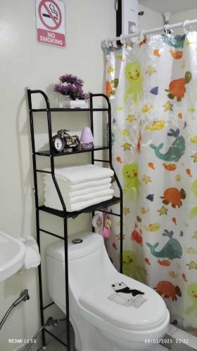a bathroom with a toilet and a shower curtain at Staycation AMAIA SJDM in Tunkong Manga
